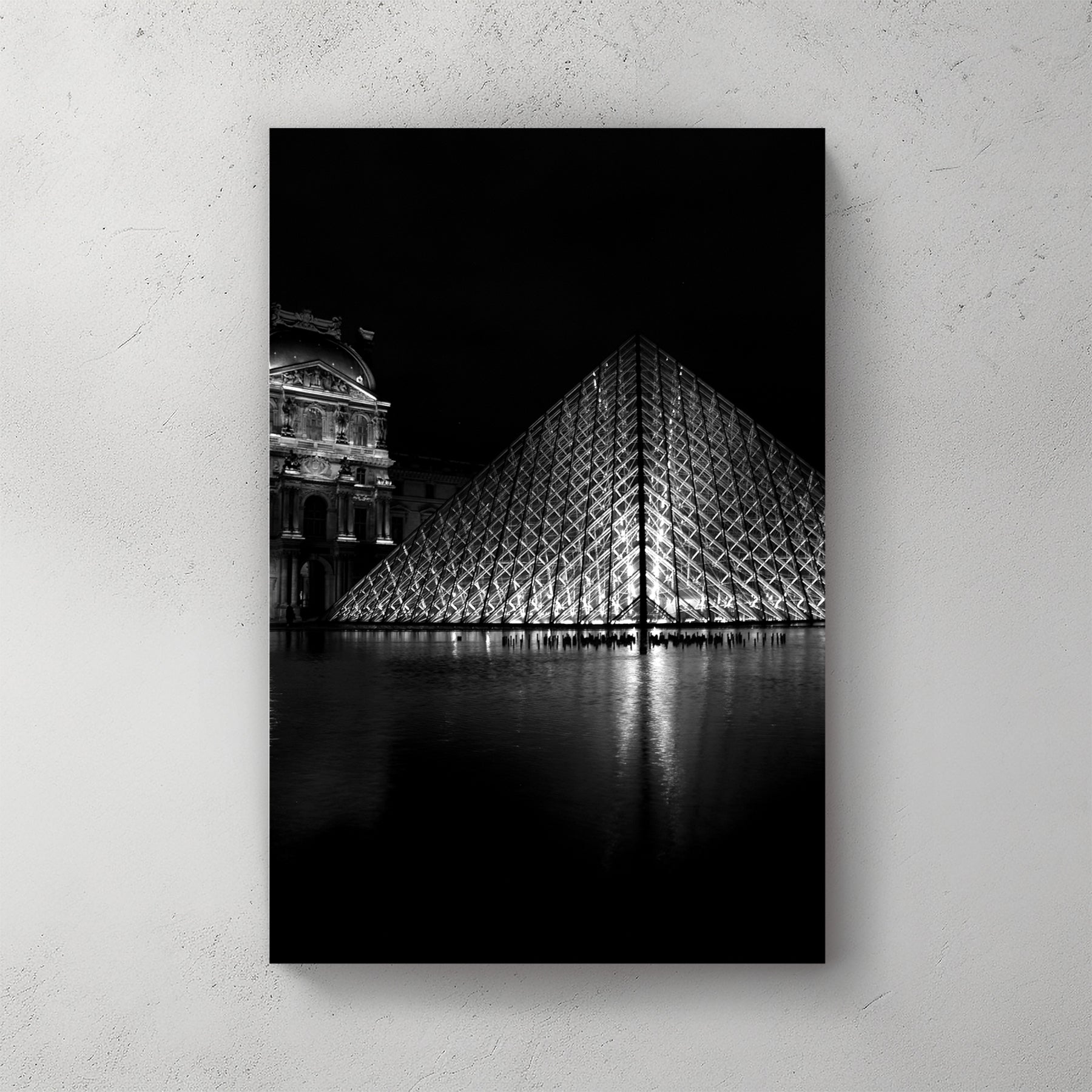 Black-and-white Louvre glass pyramid lit at night, mirrored in the courtyard pool beside the old palace — canvas wall art print