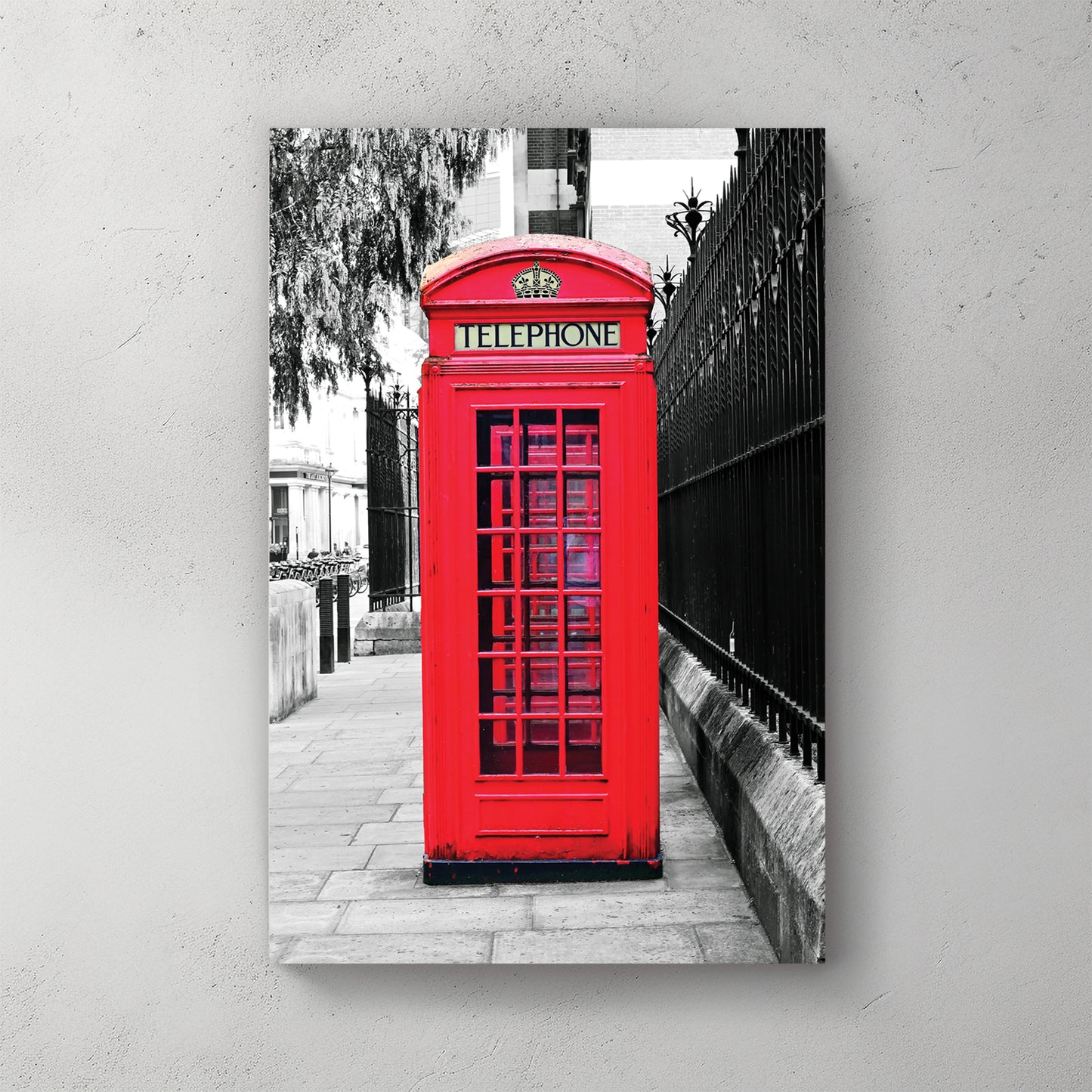 Iconic red London phone box in sharp spot-colour against a black-and-white street and iron railing — canvas wall art print