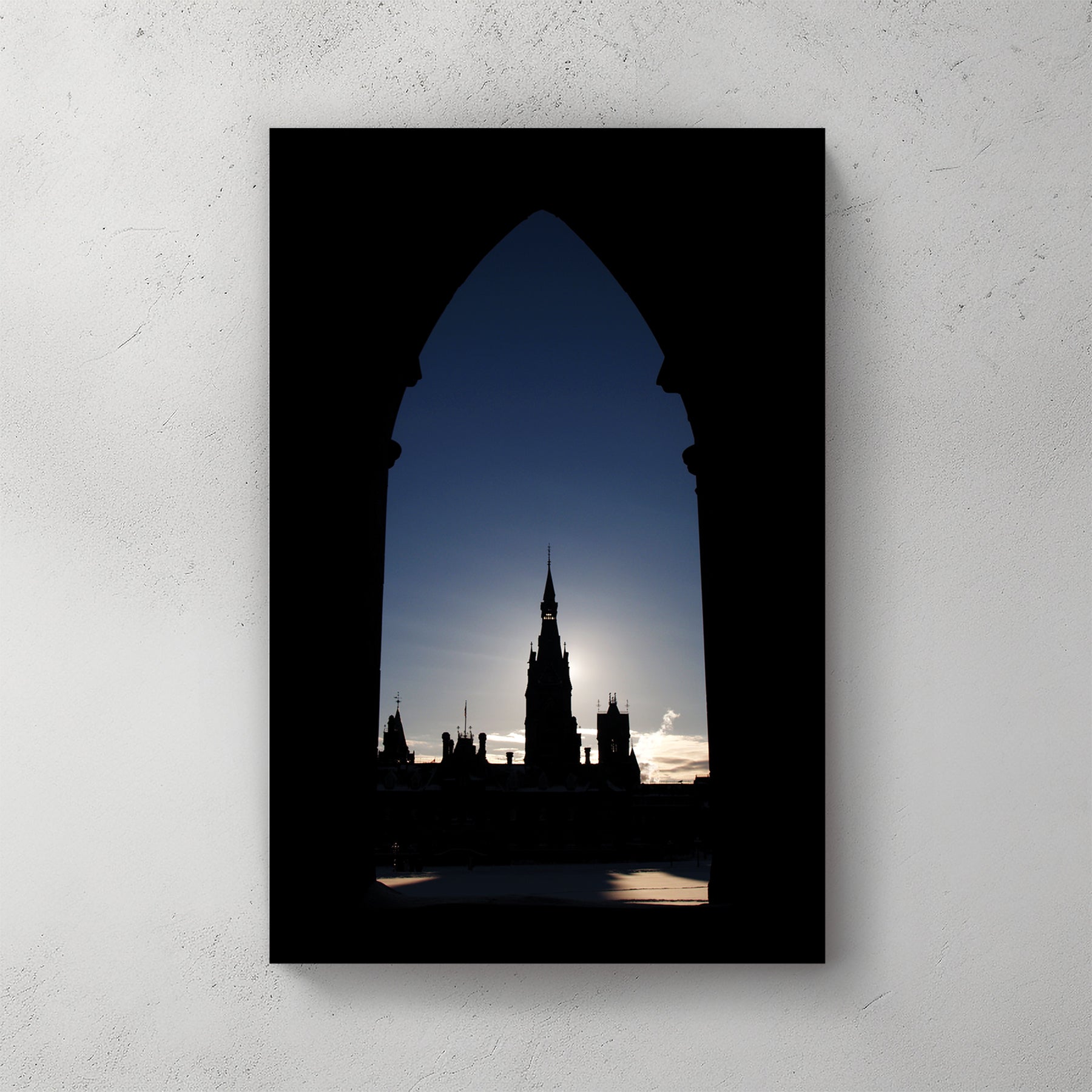 Ottawa's Parliament spire framed in a Gothic stone arch, backlit by a pale winter sun — canvas wall art print