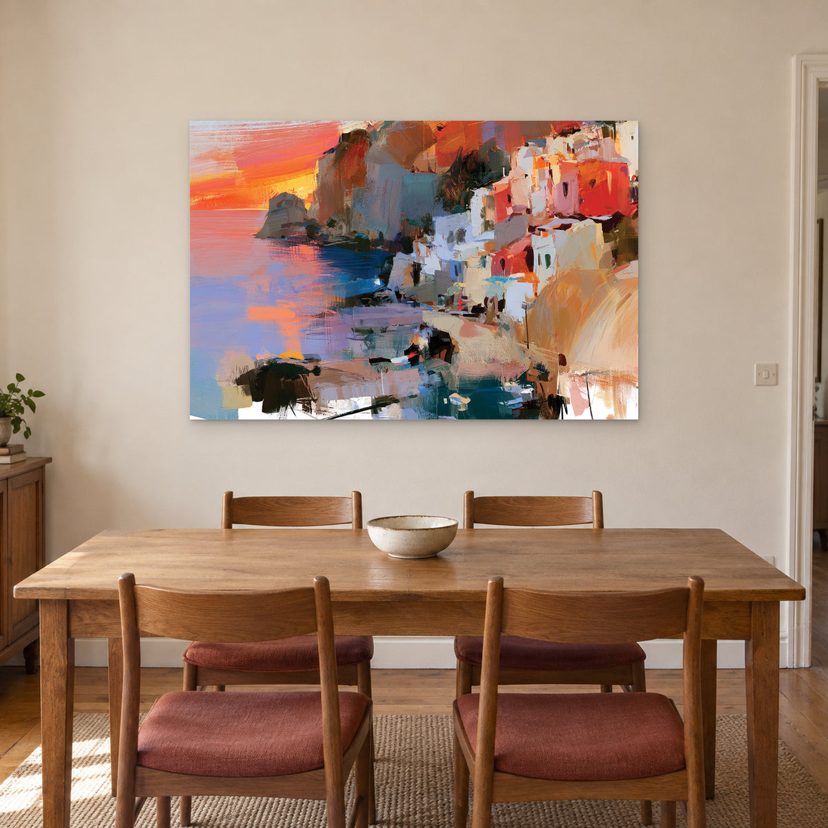 Coastal Town Sunset Headland canvas wall art above a wooden dining table with rust-cushioned chairs