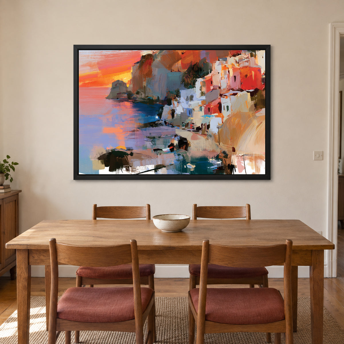 Coastal Town Sunset Headland framed canvas in a black floating frame above a wooden dining table with rust-cushioned chairs