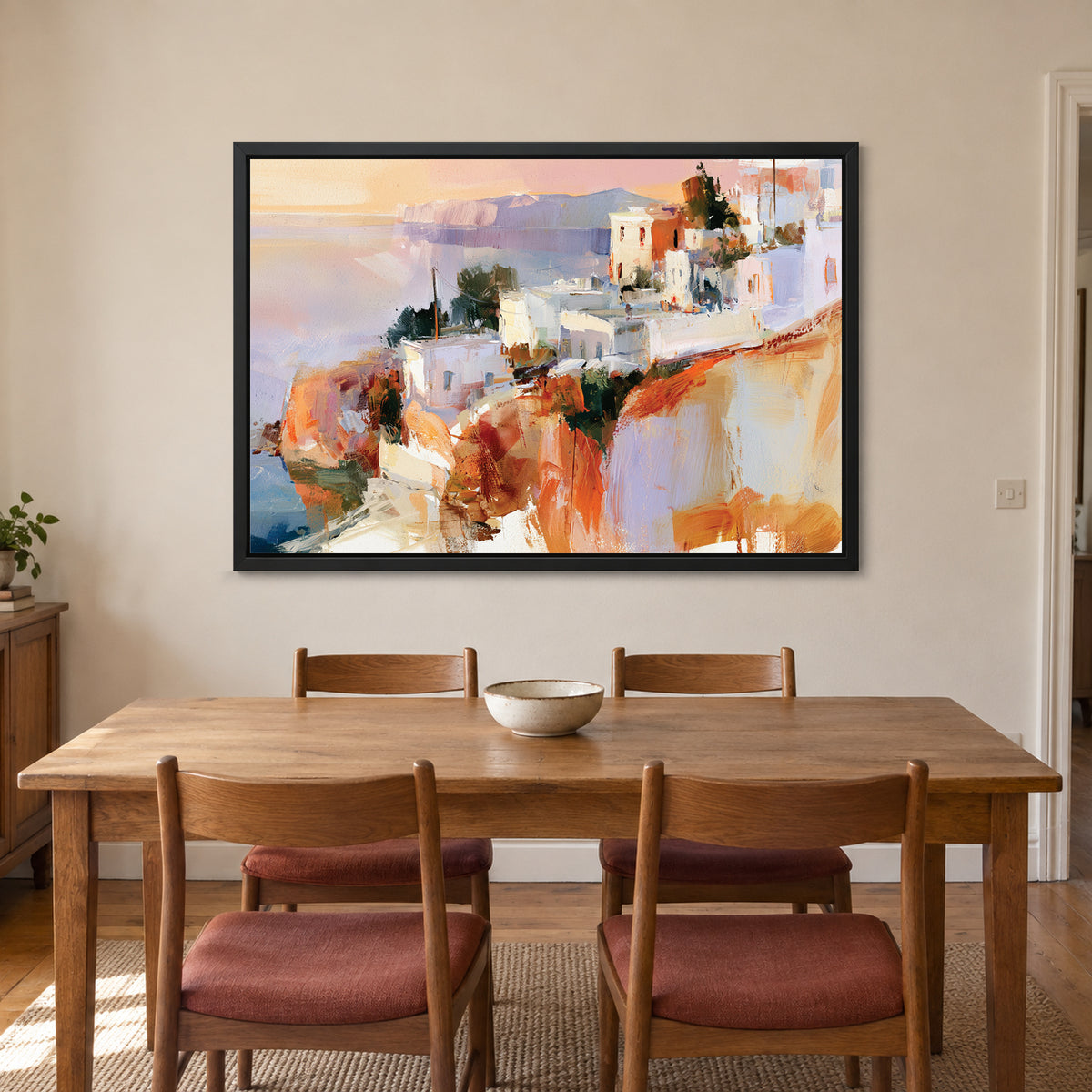 Greek Island Cliff Town framed canvas in a black floating frame above a wooden dining table with rust-cushioned chairs