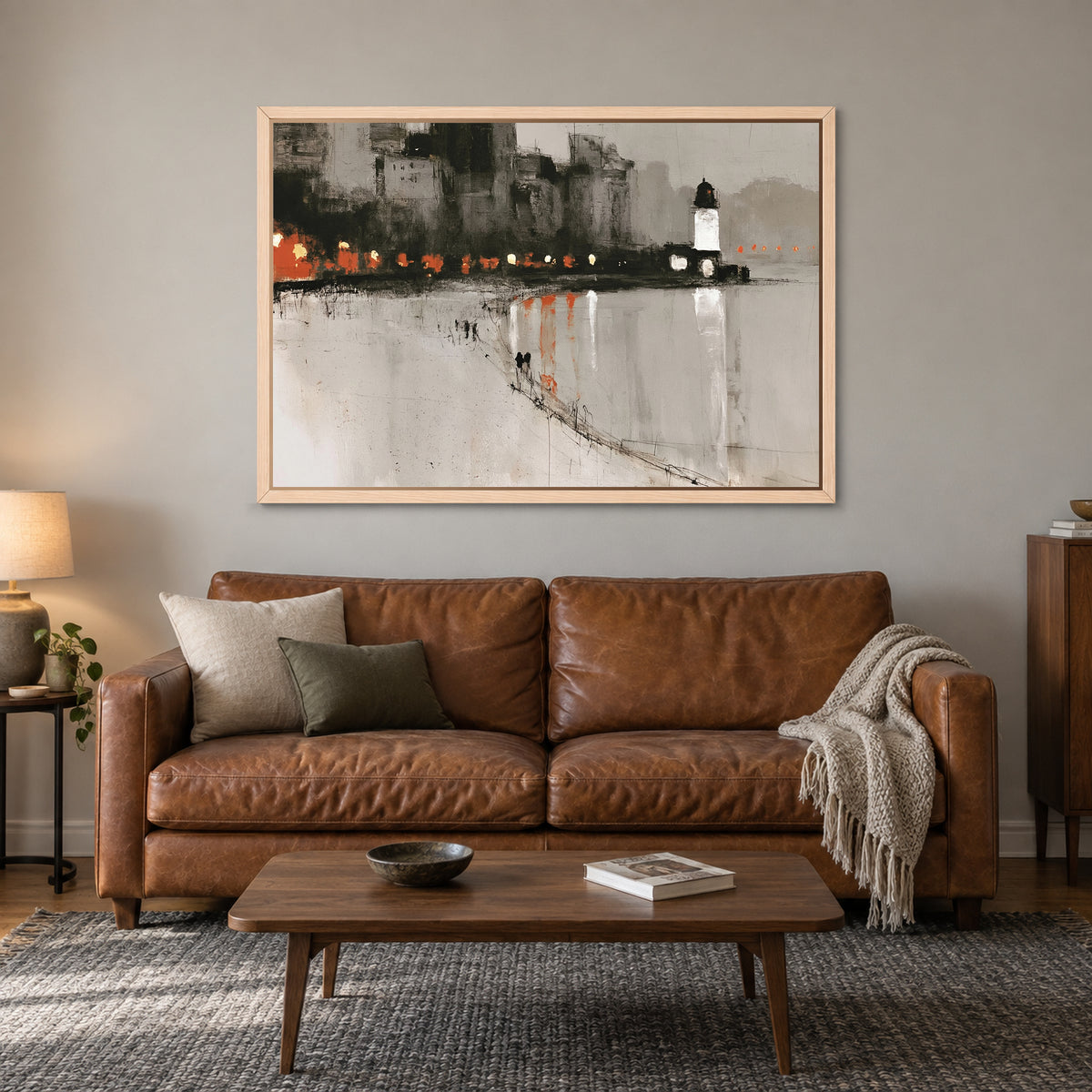 Harbour Lighthouse Night Lights framed canvas in a natural wood floating frame above a cognac leather sofa with a wooden coffee table