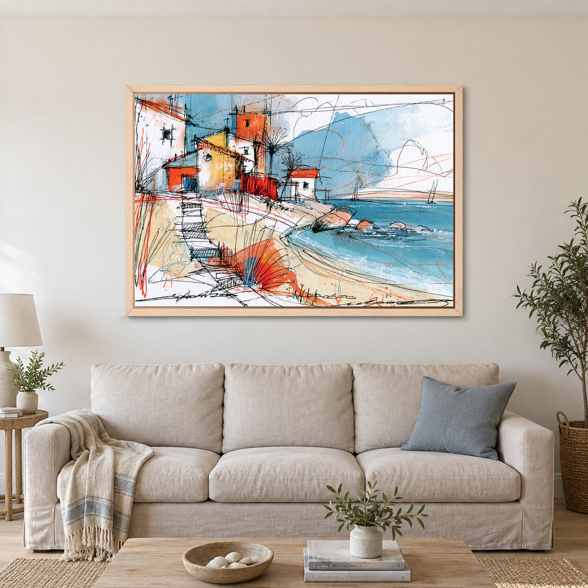 Coastal Cottages Ink Sketch framed canvas in a natural wood floating frame above a linen sofa with a blue cushion