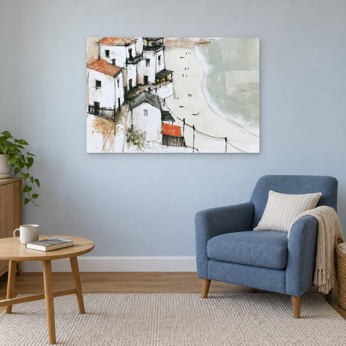 Whitewashed Headland Beach canvas wall art above a blue armchair and round wooden side table in a reading corner