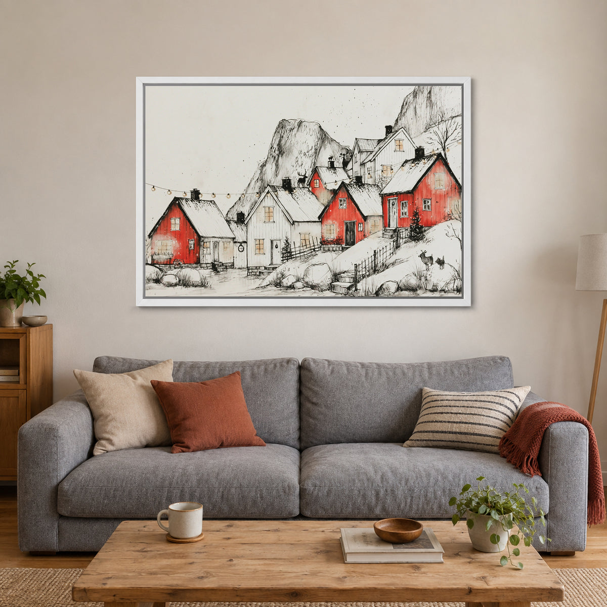 Norwegian Red Cabins Snow framed canvas in a white floating frame above a grey sofa with rust and striped cushions