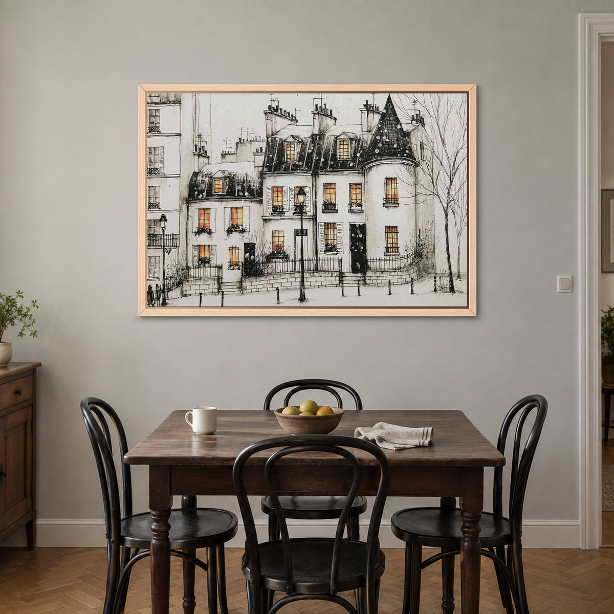 Paris Turret Rooftops Snow framed canvas in a natural wood floating frame above a small wooden dining table with black bentwood chairs