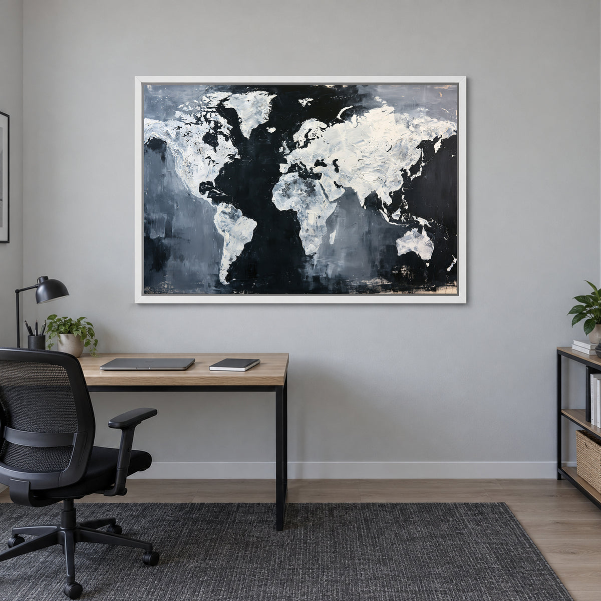 World Map Black and White framed canvas in a white floating frame above a light wood desk with a black office chair in a home office