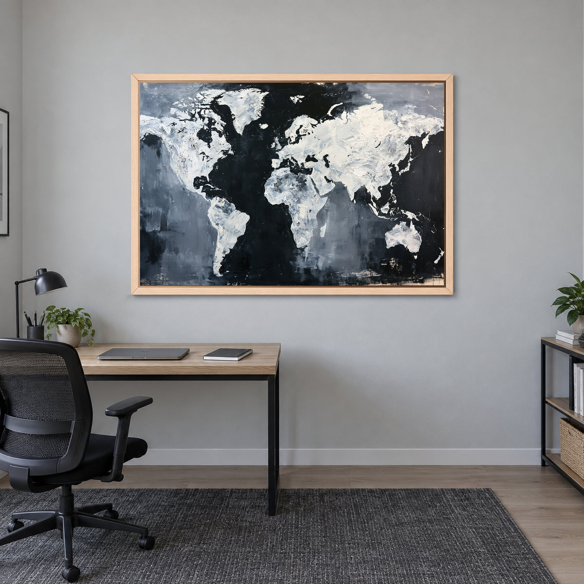 World Map Black and White framed canvas in a natural wood floating frame above a light wood desk with a black office chair in a home office
