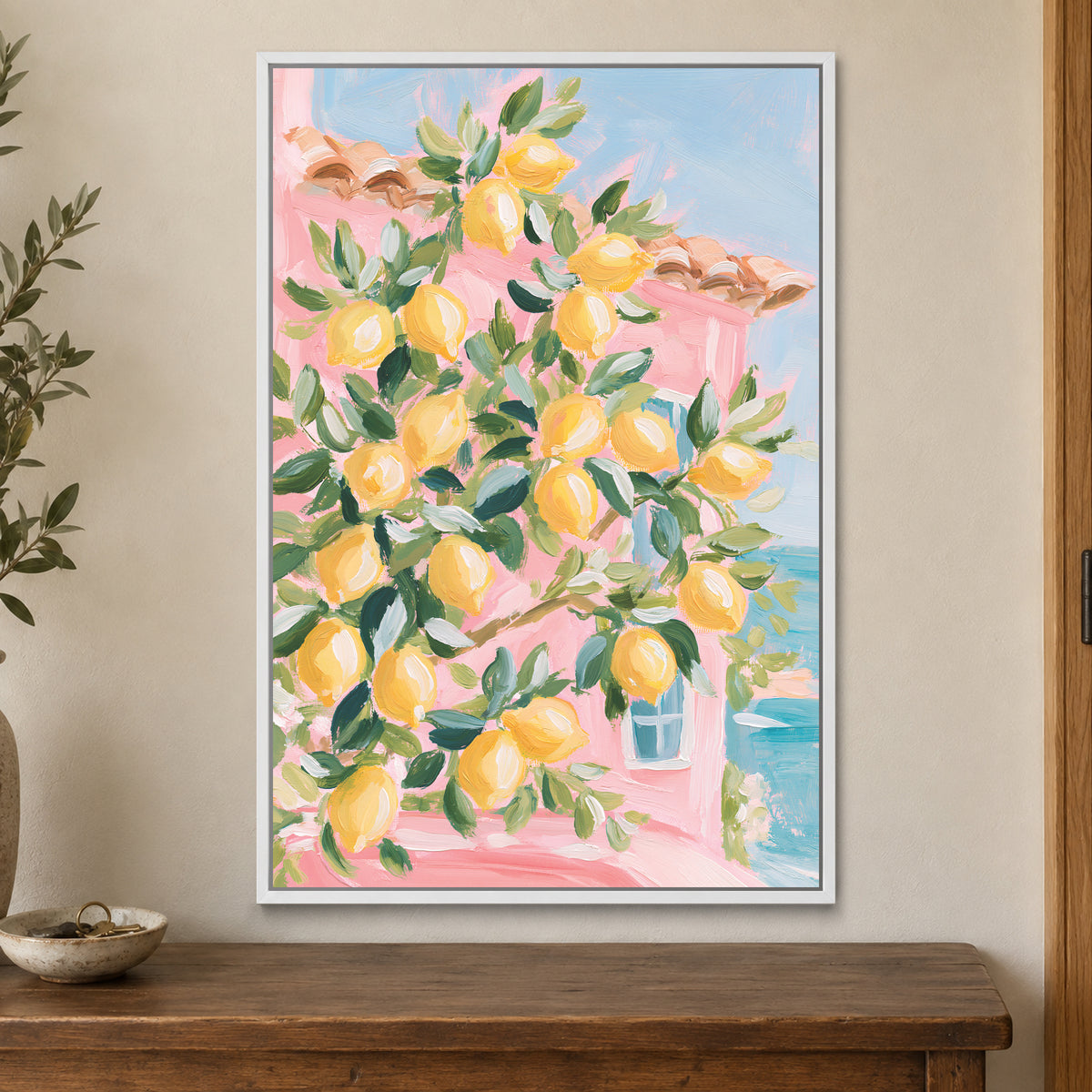 Lemon Tree and Blue Shutters framed canvas in a white floating frame on a cream wall above a wooden sideboard beside a door frame