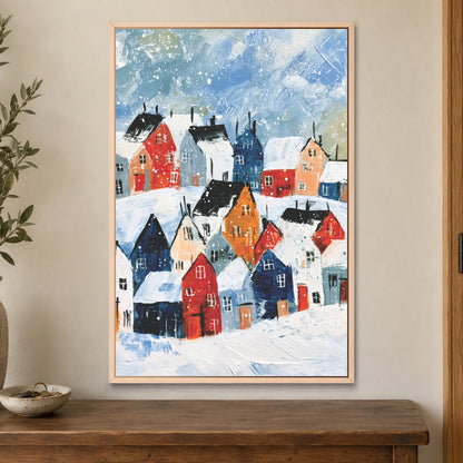 Snowfall Over the Rooftops framed canvas in a natural wood floating frame on a cream wall above a wooden sideboard beside a door frame