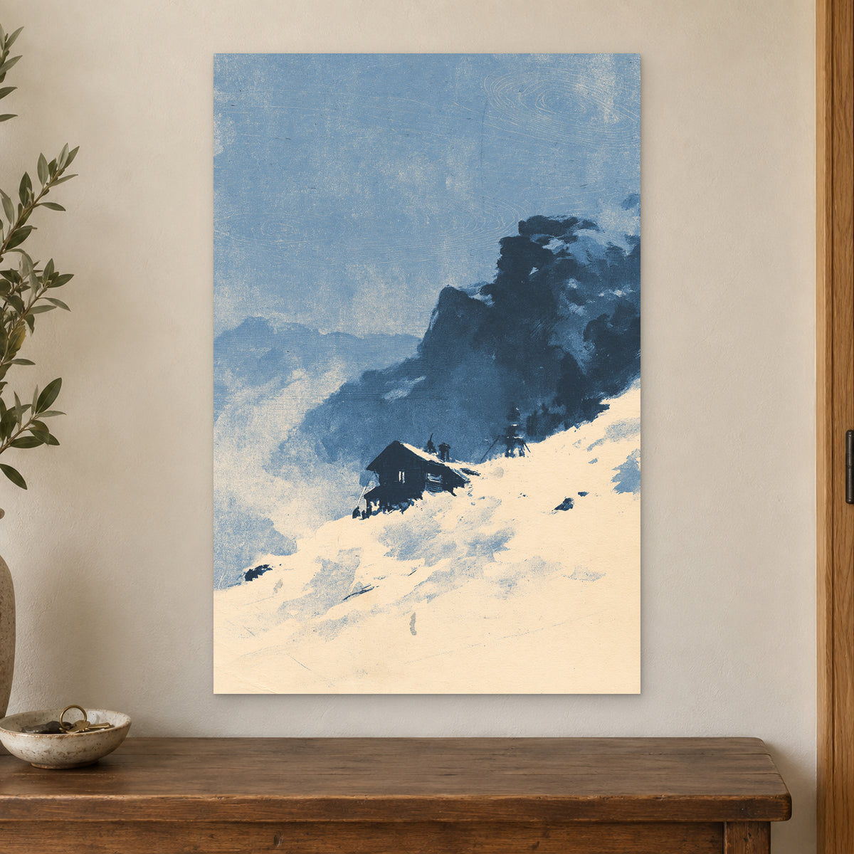Lone Cabin Snow Slope canvas wall art on a cream wall above a wooden sideboard beside a door frame