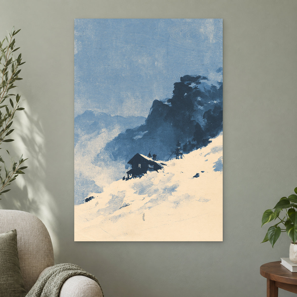 Lone Cabin Snow Slope canvas wall art on a sage green wall beside a cream armchair