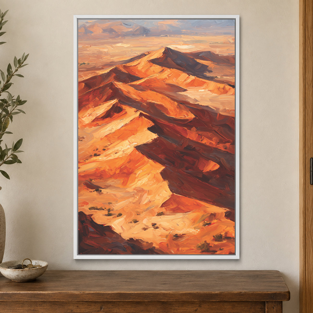 Desert Dunes Aerial Ridge framed canvas in a white floating frame on a cream wall above a wooden sideboard beside a door frame