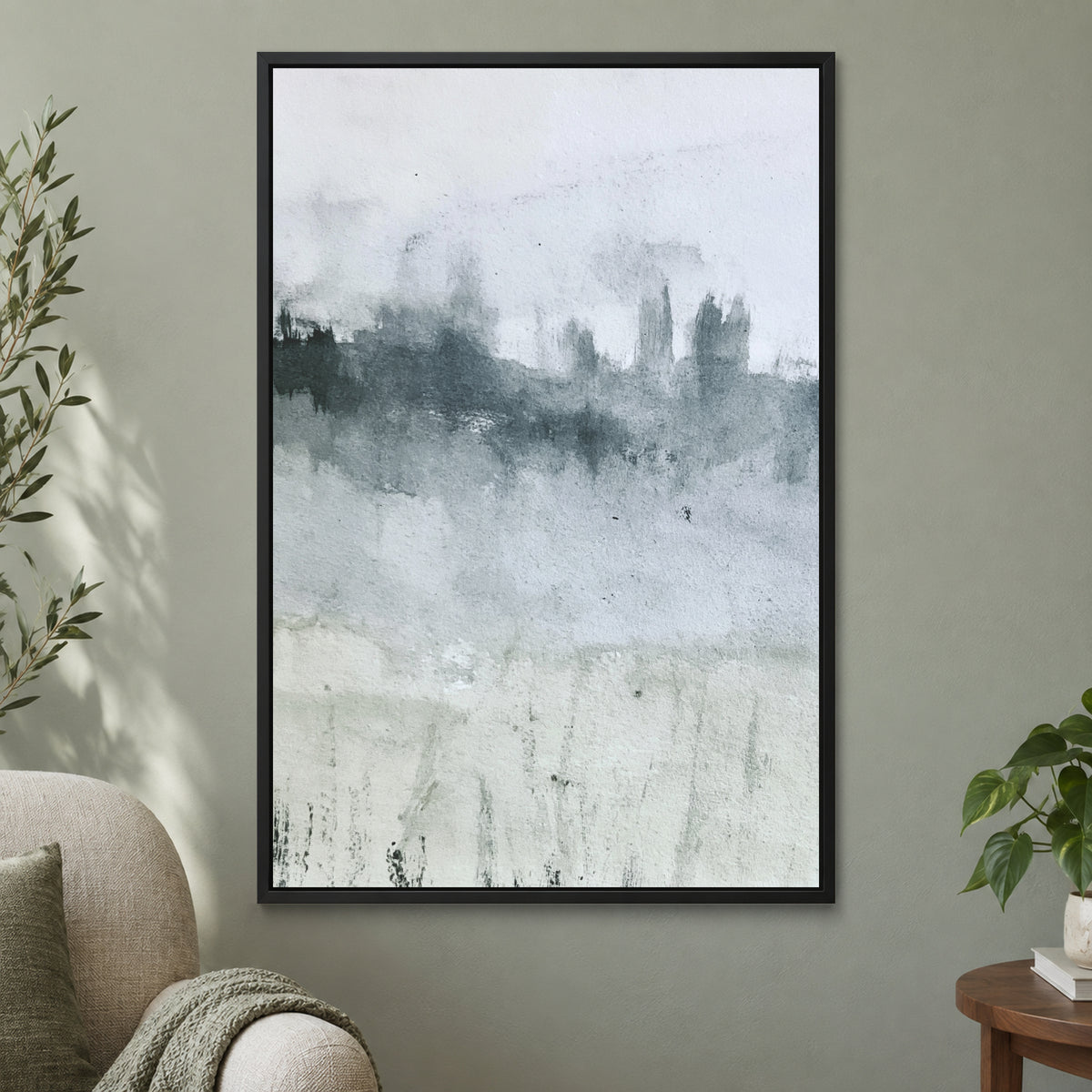 Misty Treeline Minimalist framed canvas in a black floating frame on a sage green wall beside a cream armchair