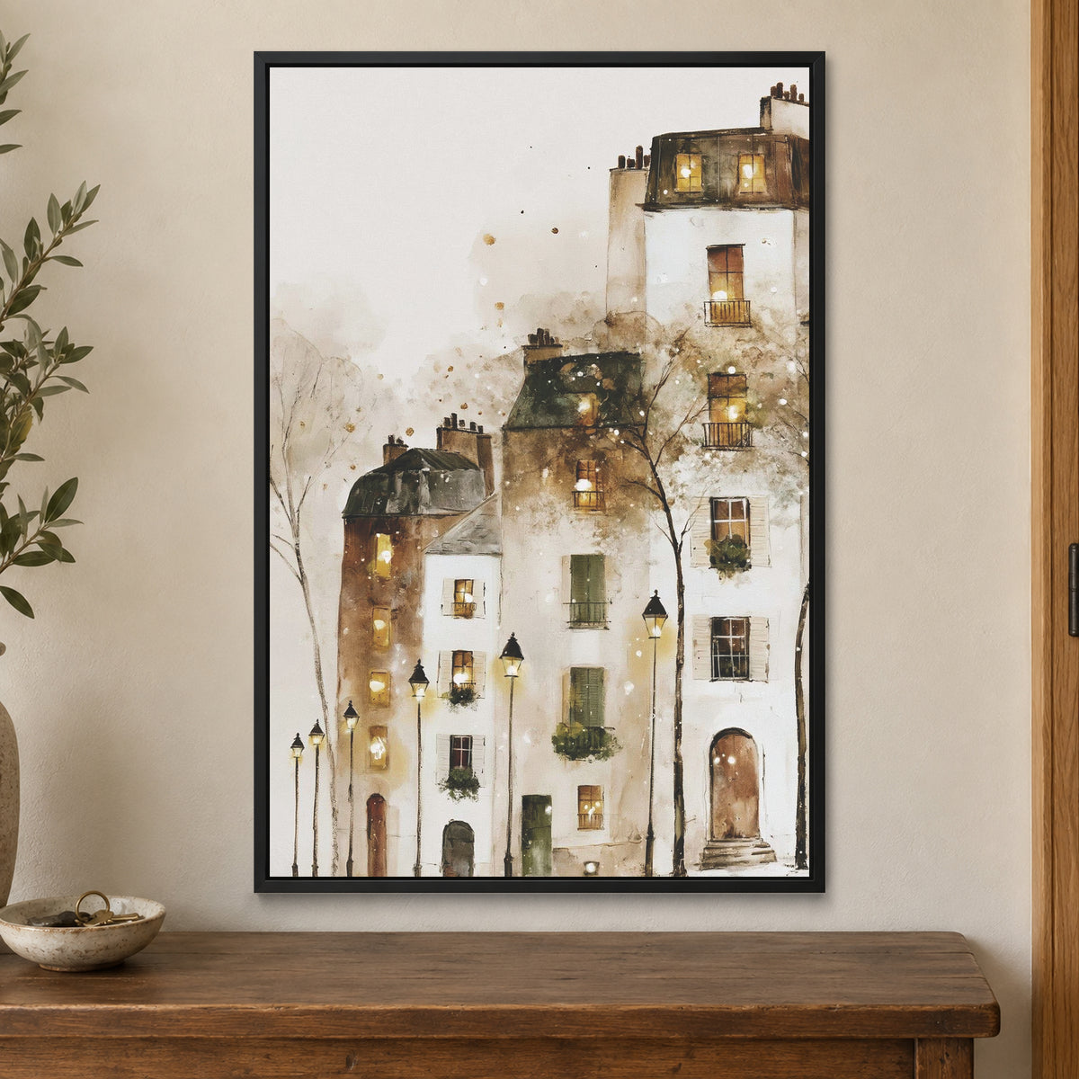 Paris Rooftops in the Snow framed canvas in a black floating frame on a cream wall above a wooden sideboard beside a door frame