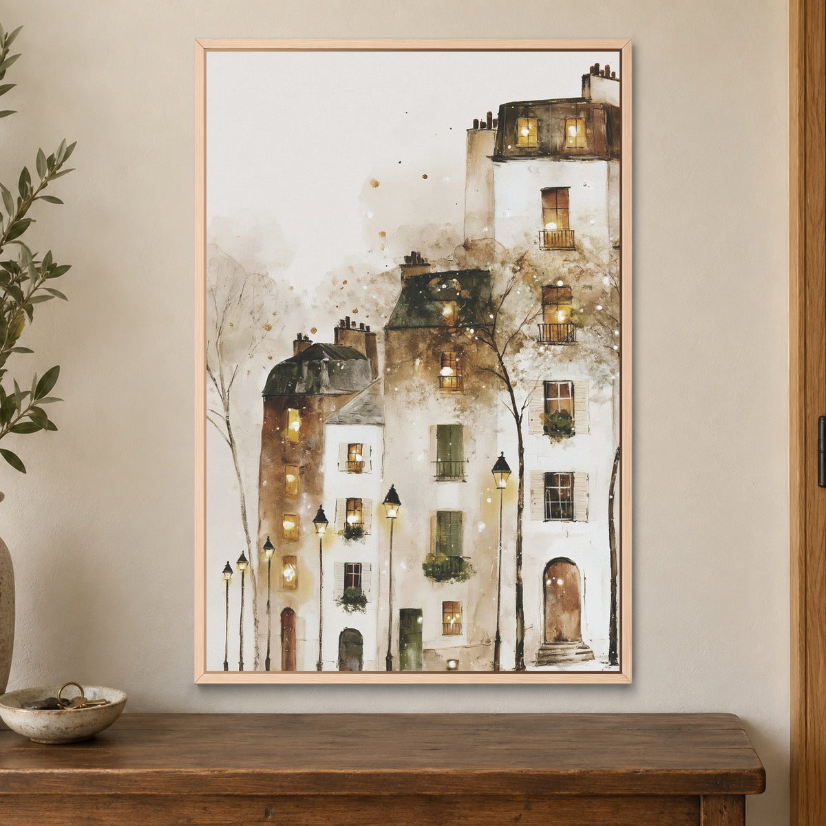 Paris Rooftops in the Snow framed canvas in a natural wood floating frame on a cream wall above a wooden sideboard beside a door frame