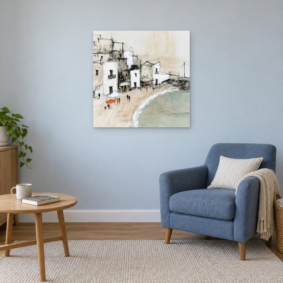 Whitewashed Seaside Village canvas wall art above a blue armchair and round wooden side table in a reading corner