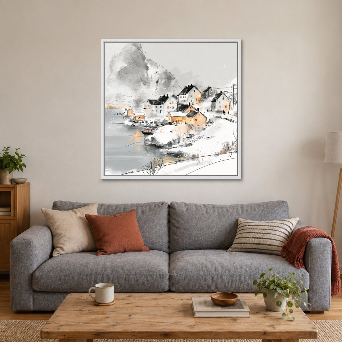 Snowy Nordic Harbour Village framed canvas in a white floating frame above a grey sofa with rust and striped cushions