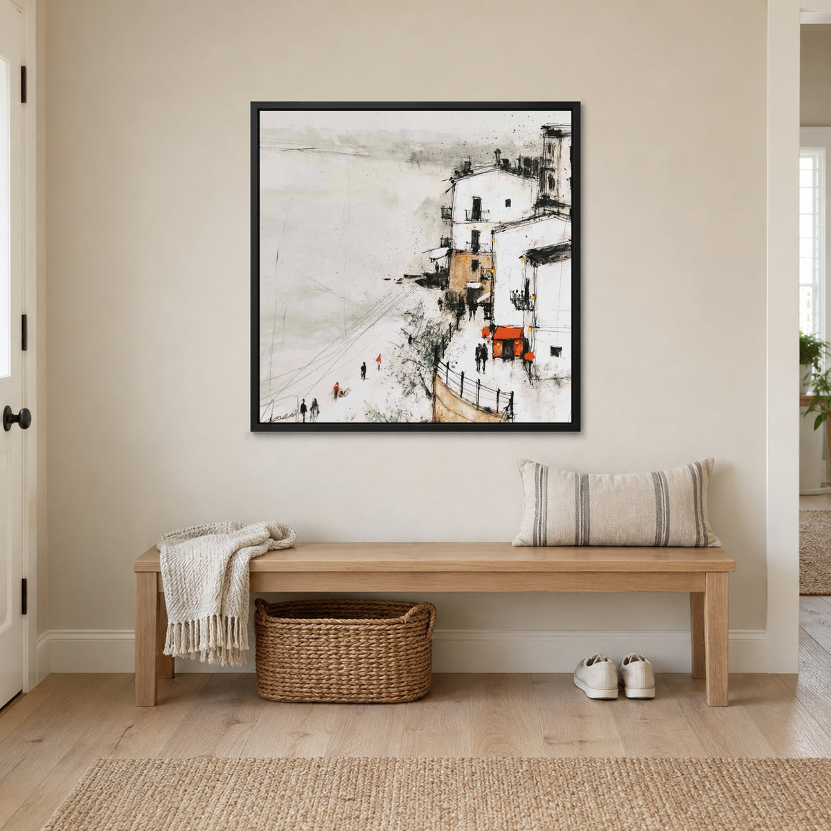 Sicilian Cliff Town Above the Sand framed canvas in a black floating frame above a wooden entryway bench with a woven basket