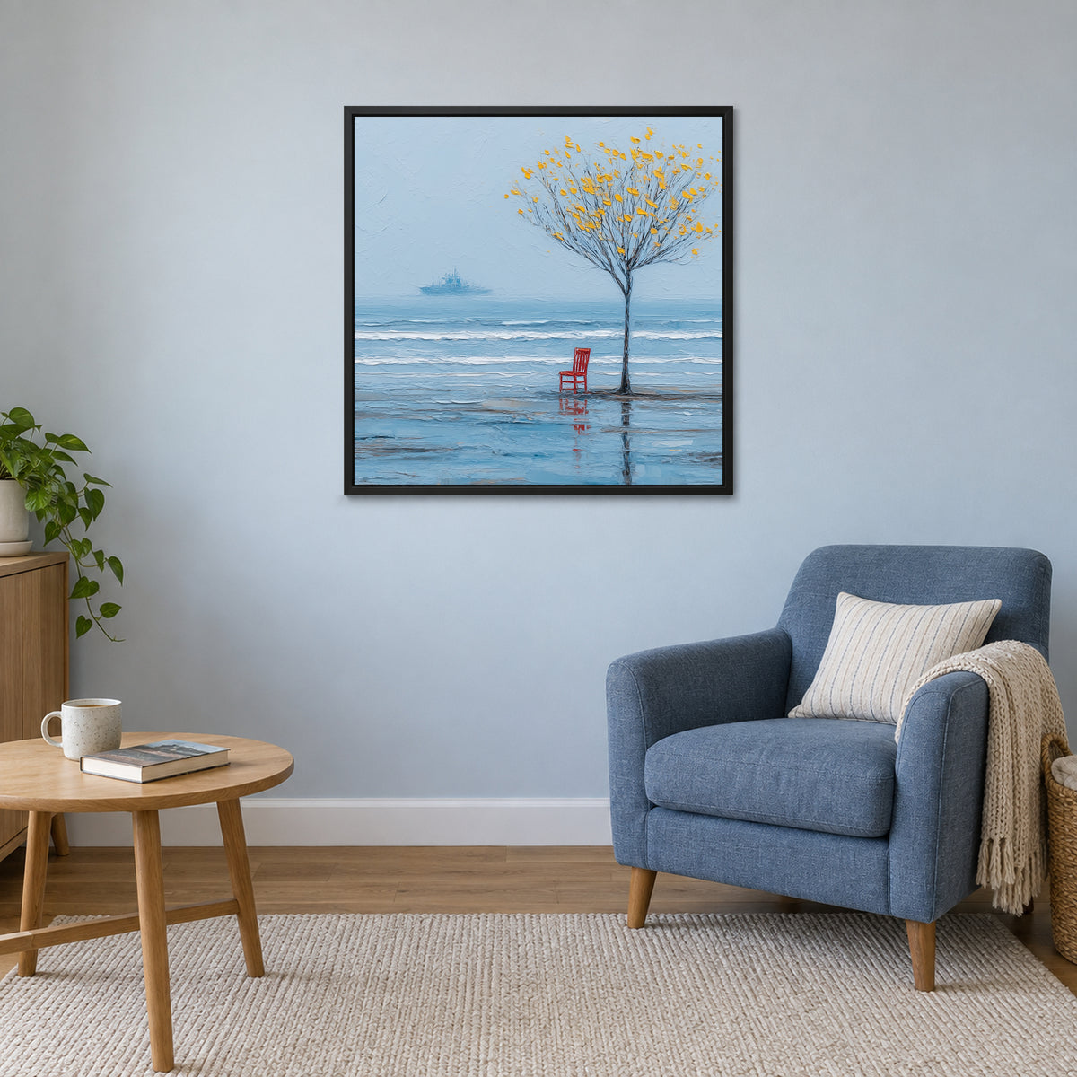 A Red Chair by the Sea framed canvas in a black floating frame above a blue armchair and round wooden side table