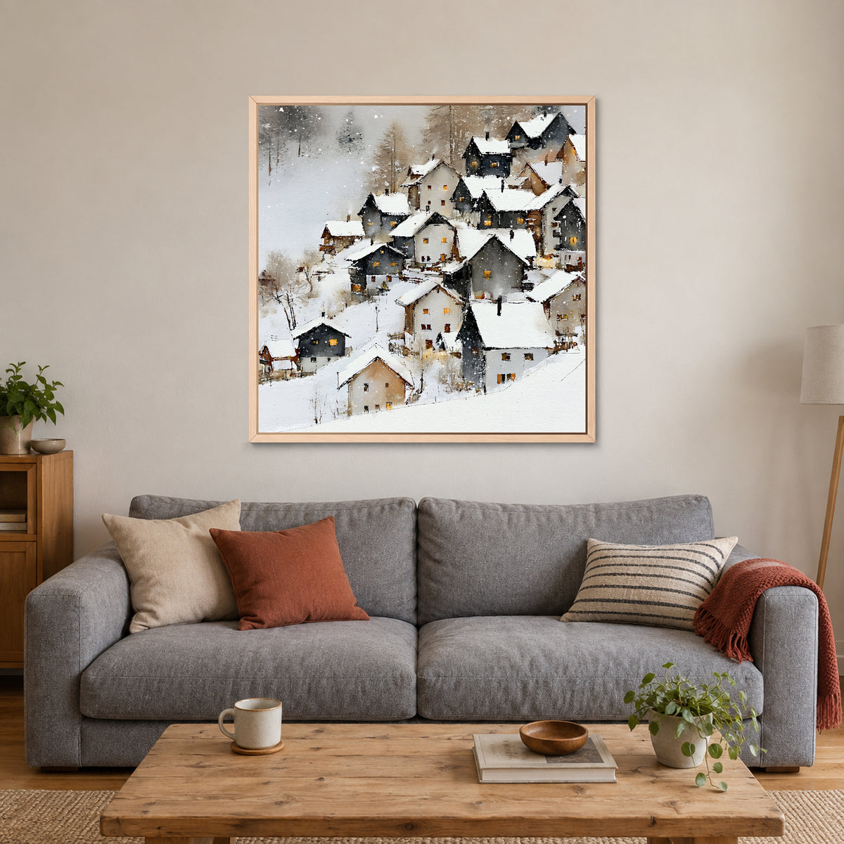 Alpine Chalets in Heavy Snow framed canvas in a natural wood floating frame above a grey sofa with rust and striped cushions