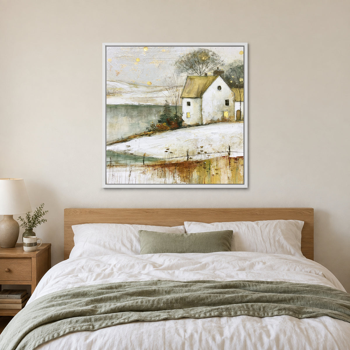 Gold Flecks Over a Frozen Lake framed canvas in a white floating frame above a bed with white linens and a sage throw