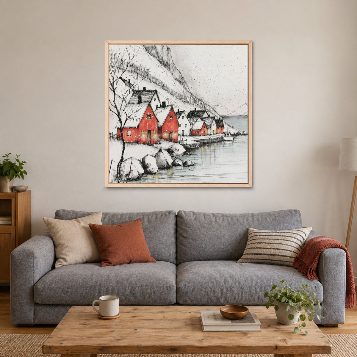 Scandinavian Red Boathouses Winter framed canvas in a natural wood floating frame above a grey sofa with rust and striped cushions